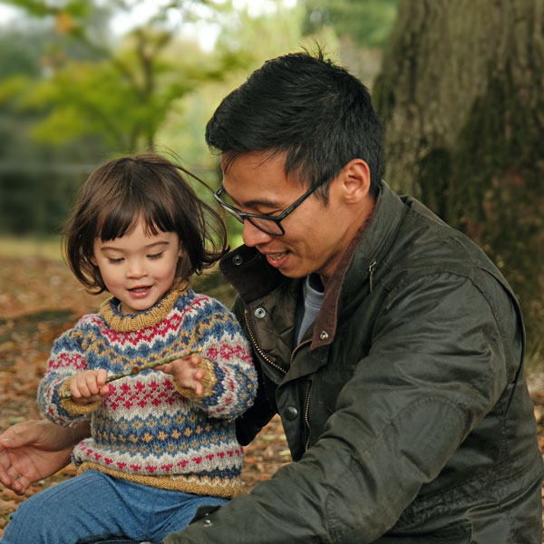 Child and father sitting by tree