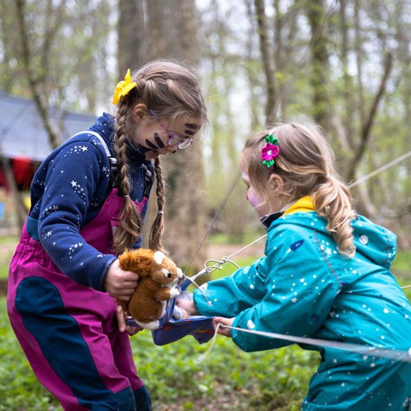girls playing with cuddly toy in woods